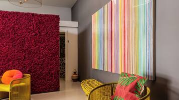 A modern interior with a red textured wall, a large colorful striped artwork, and a yellow wicker chair with a red pillow.