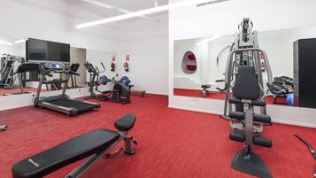 Un gimnasio con cintas de correr, máquinas de pesas y pelotas de ejercicio.