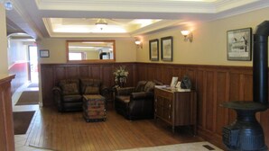 A spacious living area with a wooden floor, a fireplace, and a large mirror on the wall. - Reynolds Hotel (Lillooet)