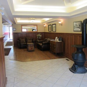 A spacious living area with a wooden floor, a fireplace, and a large mirror on the wall. - Reynolds Hotel (Lillooet)
