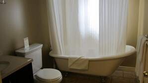 A bathroom with a toilet, a bathtub, and a sink. - Reynolds Hotel (Lillooet)