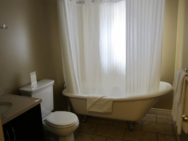 A bathroom with a toilet, a bathtub, and a sink. - Reynolds Hotel (Lillooet)
