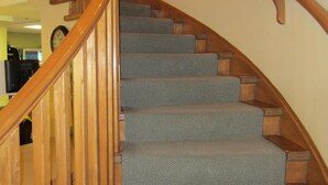 A wooden staircase with carpeted steps and a wooden handrail. - Reynolds Hotel (Lillooet)