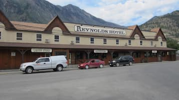 A two-story building with a sign for the Reynolds Hotel. There are parked vehicles in front.