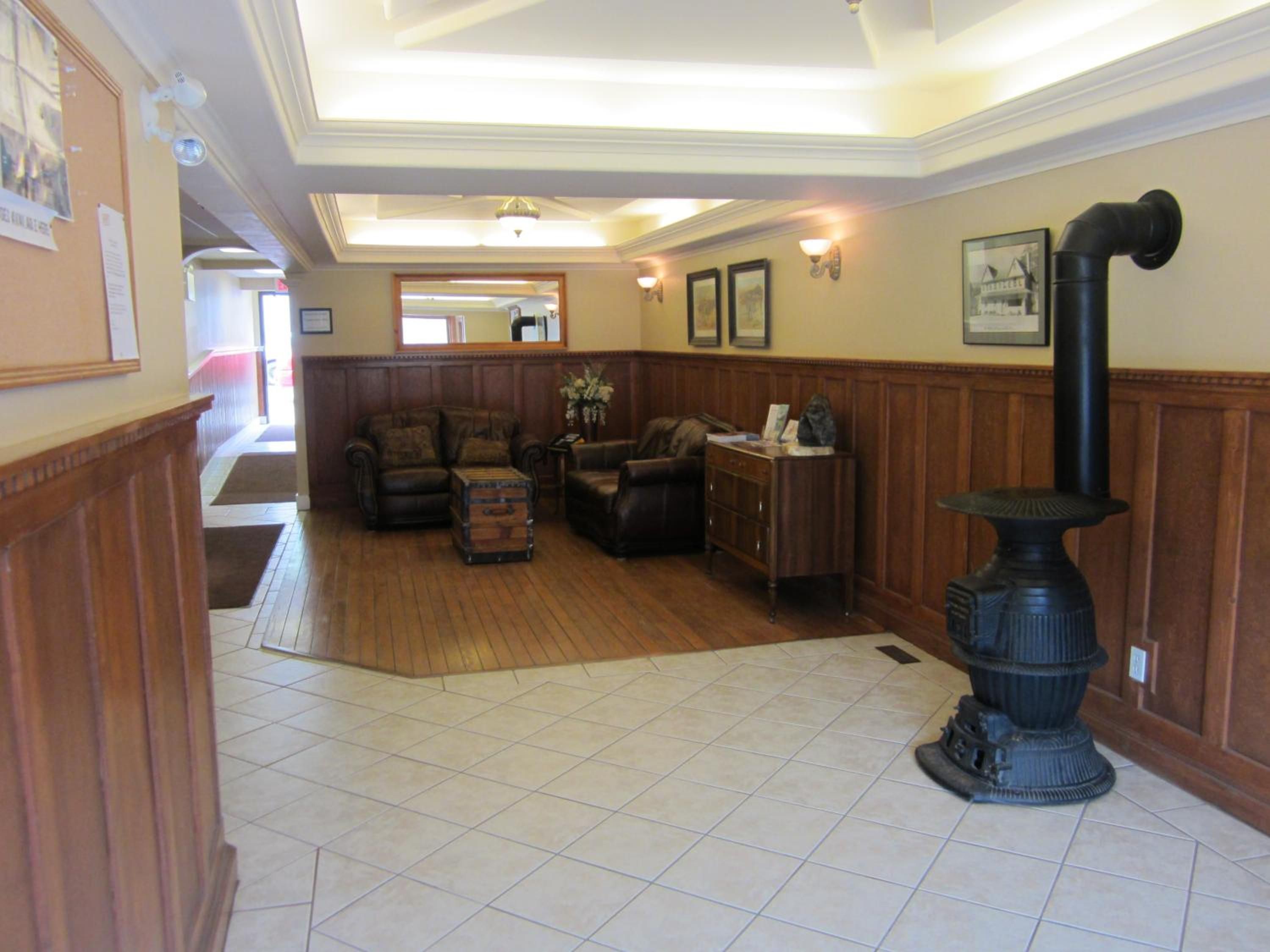 A spacious living room with a fireplace, a wooden floor, and a view of the hallway.