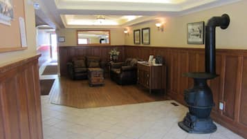 A spacious living room with a fireplace, a wooden floor, and a view of the hallway.