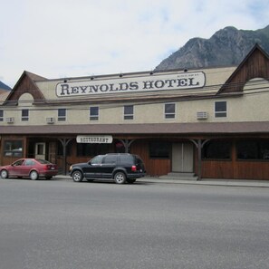 Un edificio de dos pisos con un cartel que dice 'REYNOLDS HOTEL' y un cartel de 'COOKHOUSE RESTAURANT' debajo.