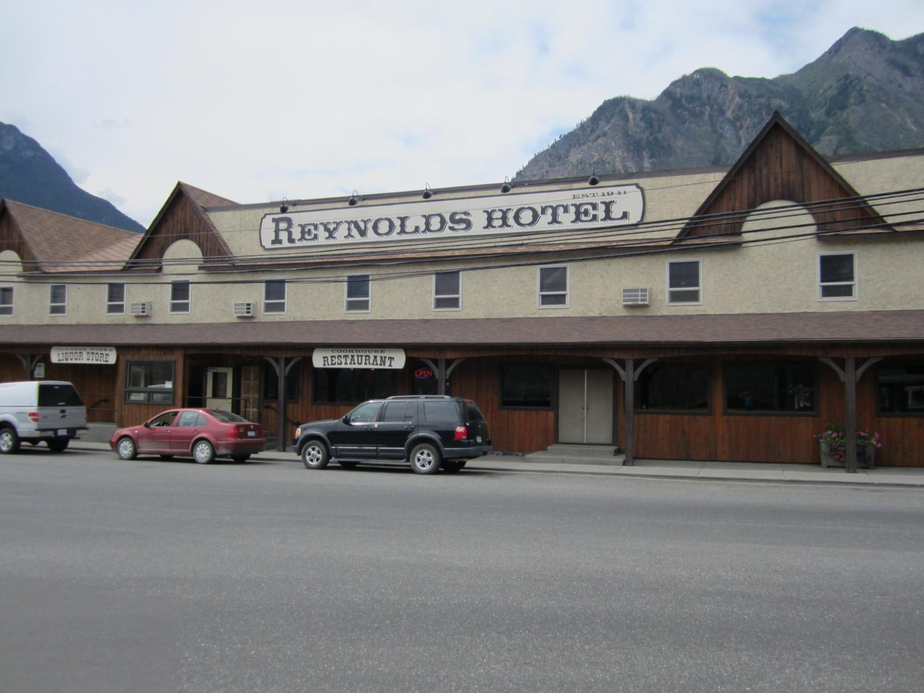 A two-story hotel with a sign reading 'REYNOLDS HOTEL' and a 'COOKHOUSE RESTAURANT' sign below.