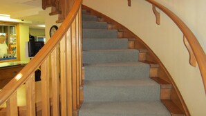 A wooden staircase with carpeted steps leading to a landing. - Reynolds Hotel (Lillooet)
