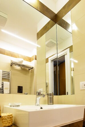 A modern bathroom with a large mirror, a white sink, and a towel rack.