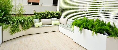 A modern outdoor seating area with built-in planters and a white fence.