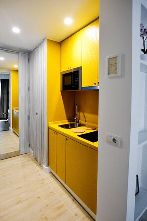 A modern kitchen with yellow cabinets, a black countertop, and a stainless steel sink.