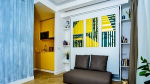 A modern living room with a sofa, a kitchen in the background, and abstract wall art. - Click&Sleep (Naples)
