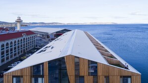 A modern building with a sloped roof, large windows, and a view of the sea. - MACq 01 Hotel (Hobart)