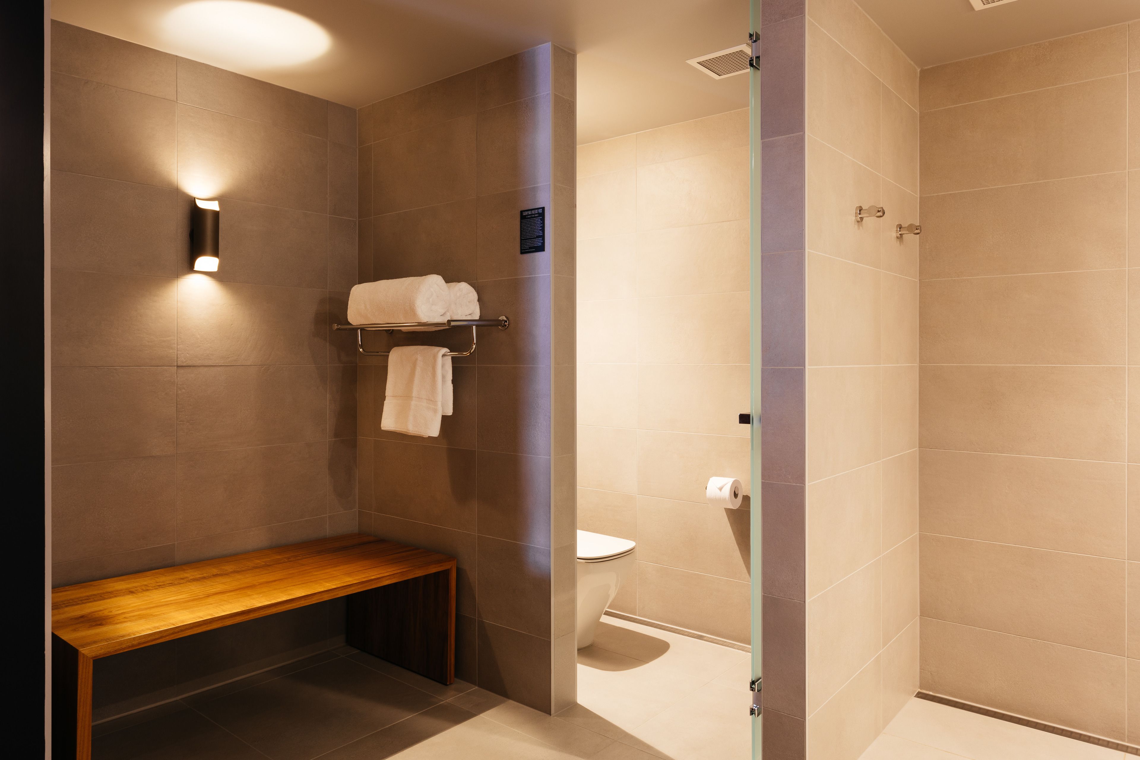 A modern bathroom with a bench, a towel rack, and a toilet.