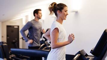 Un gimnasio con cintas de correr y una persona corriendo.
