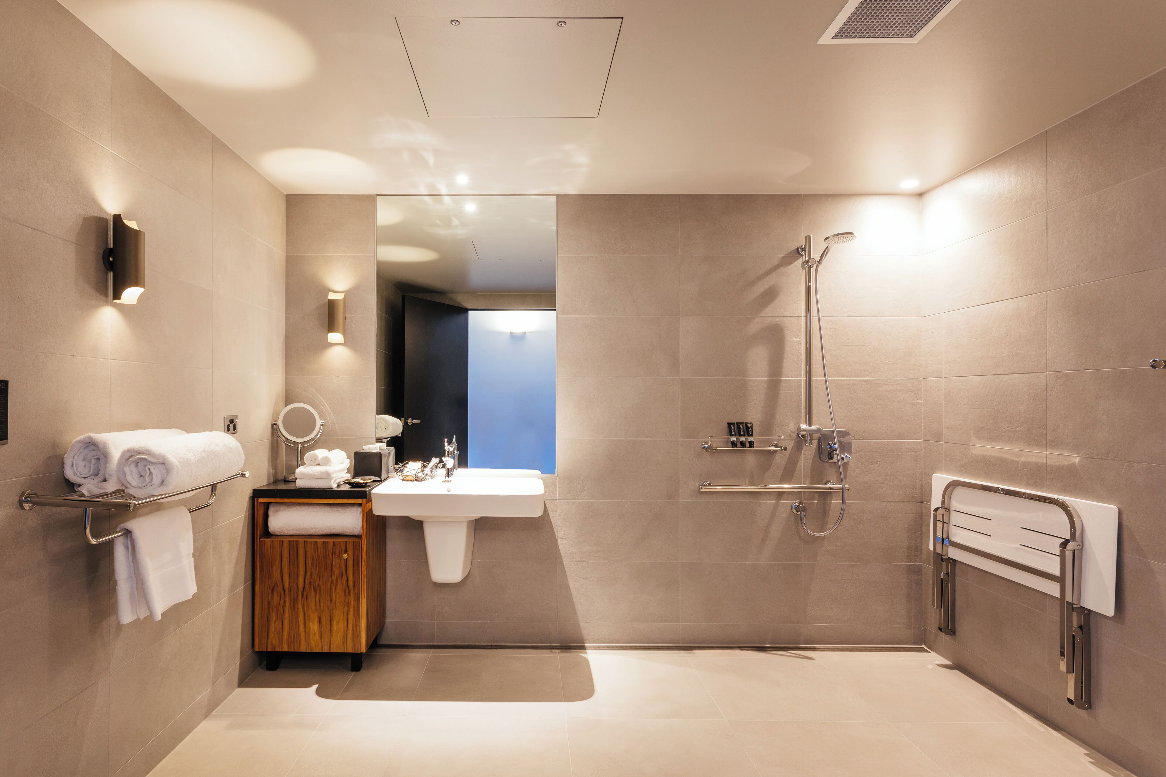 Une salle de bain moderne équipée d’une douche, d’un lavabo et d’un porte-serviettes.
