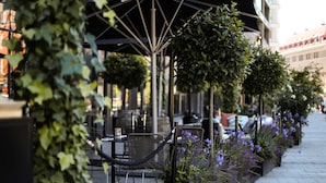 An outdoor seating area with tables and chairs, surrounded by planters with purple flowers.