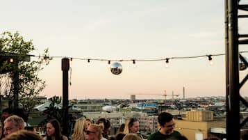 Reunión en la azotea con luces colgantes y una bola de discoteca.