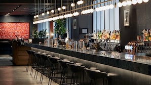 A bar area with a long counter, bar stools, and a variety of bottles and glasses.