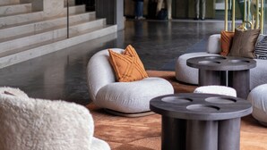 A modern lobby with a marble staircase, plush seating areas, and a large bust sculpture.