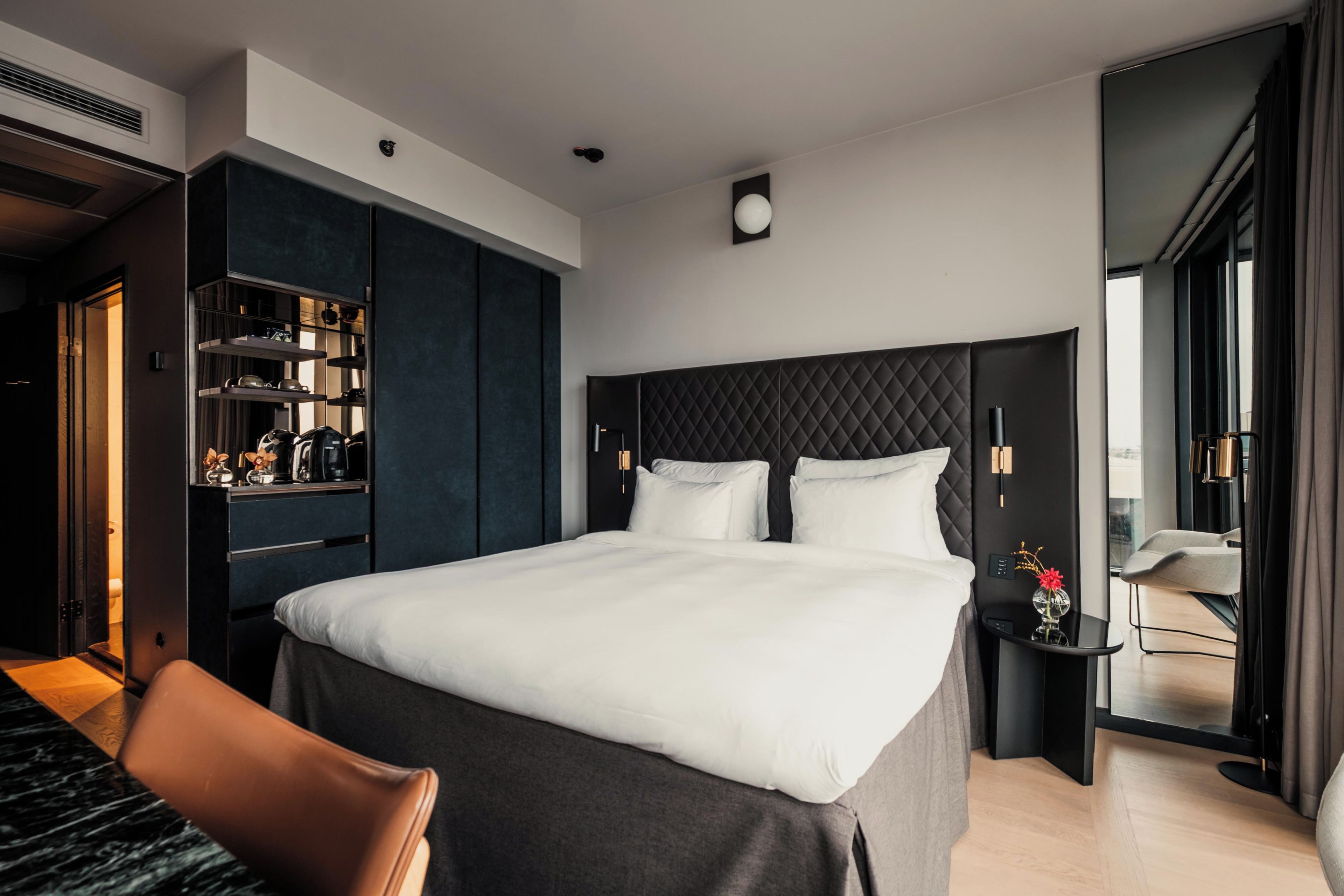 Ett modernt hotellrum med en stor säng, en inbyggd garderob, ett nattduksbord och utsikt över omgivningarna.