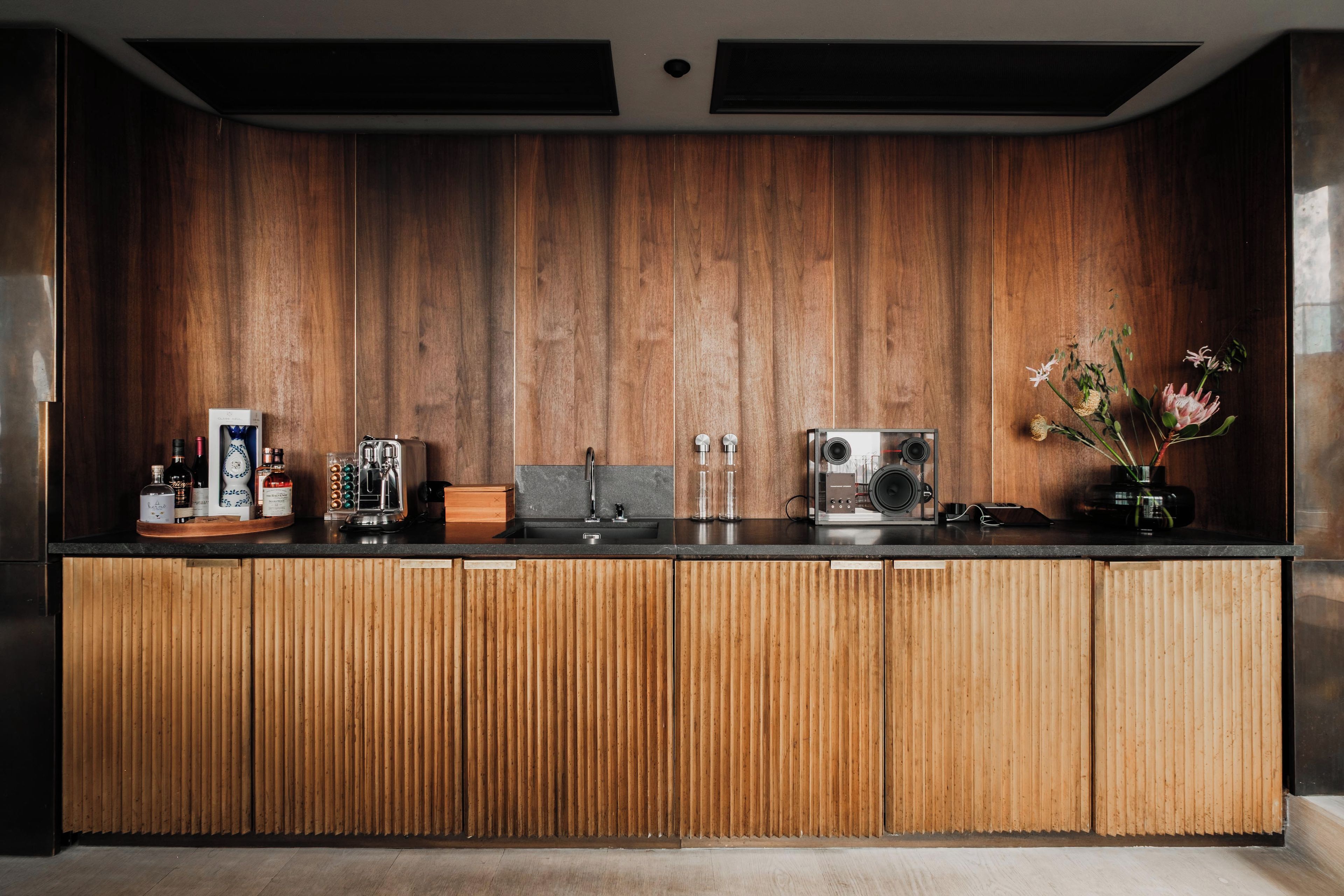 Een moderne keuken met houten keukenkastjes, een inbouwspoelbak en diverse apparaten.