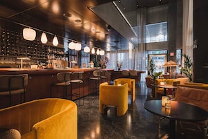 A modern bar area with a bar counter, seating with yellow chairs, and pendant lighting.