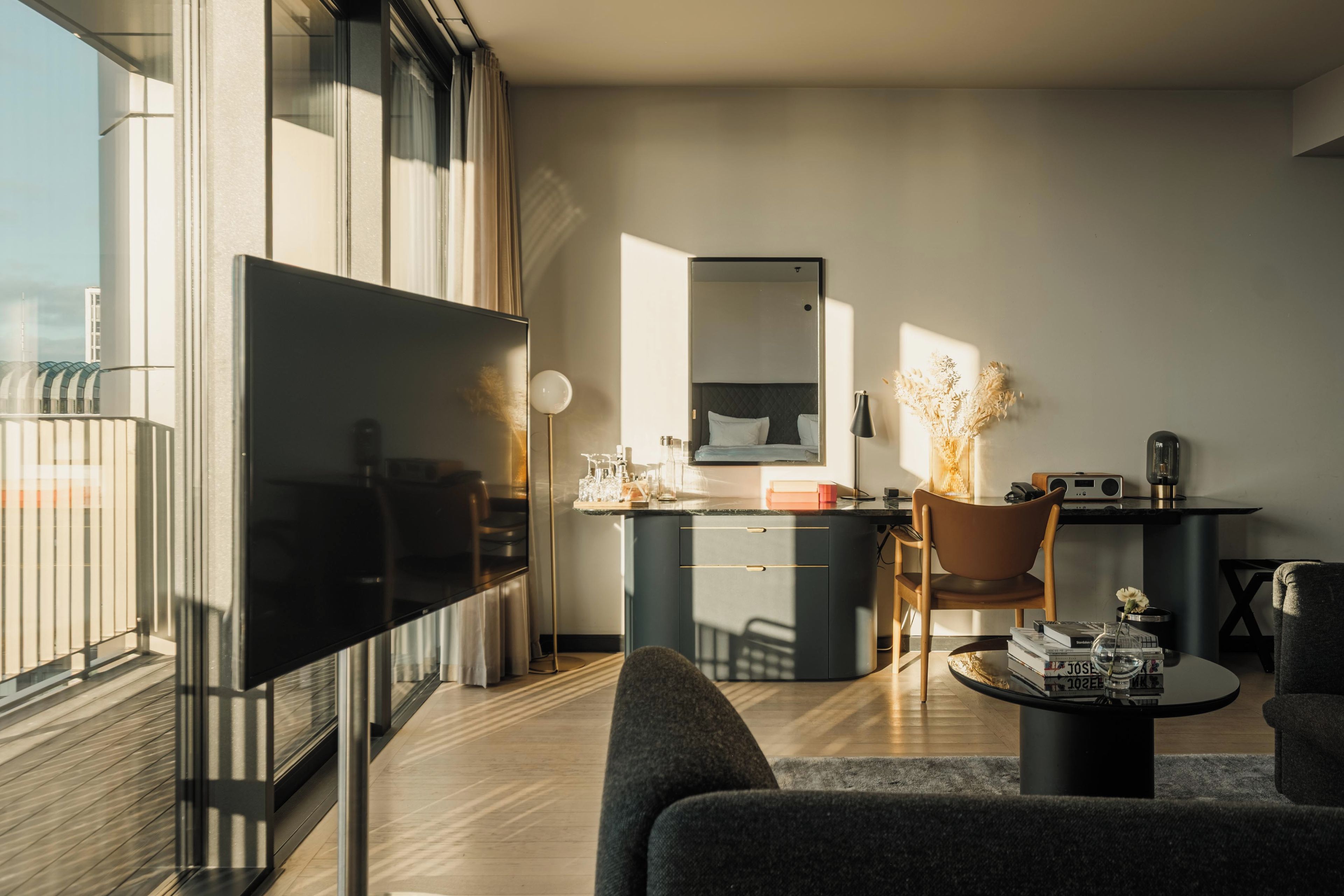 Ein modernes Wohnzimmer mit einem Flachbildfernseher, einem Schreibtisch mit Stuhl, einem Couchtisch und einer Couch.