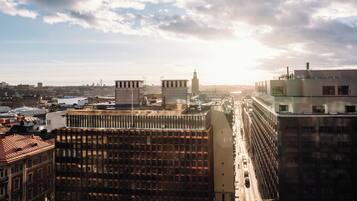 A cityscape with modern buildings, a clear sky, and a distant view of a body of water.