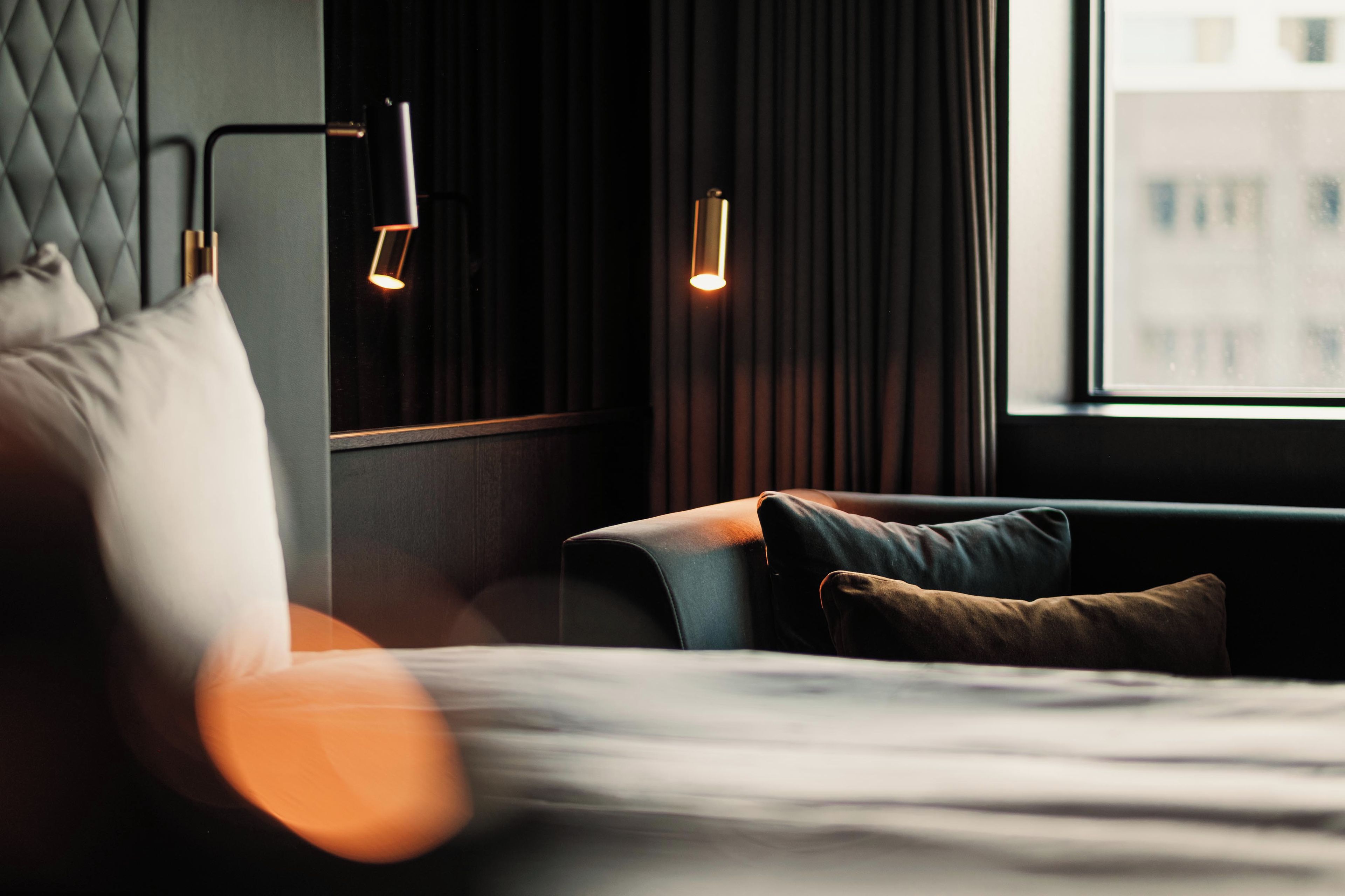 Une chambre d’hôtel moderne avec un lit, un canapé et une fenêtre.