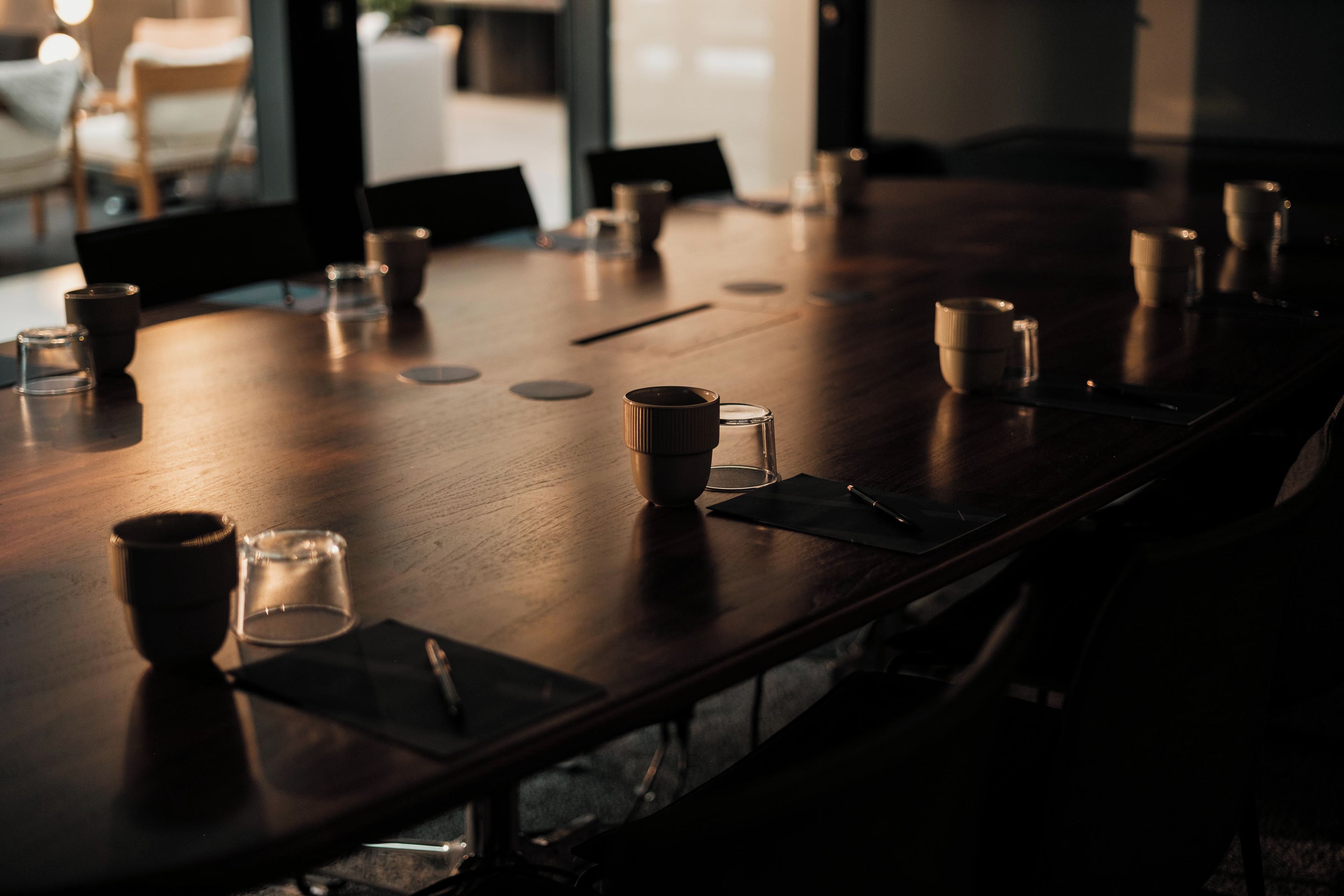 Una mesa de conferencias con sillas, vasos y un cuaderno.