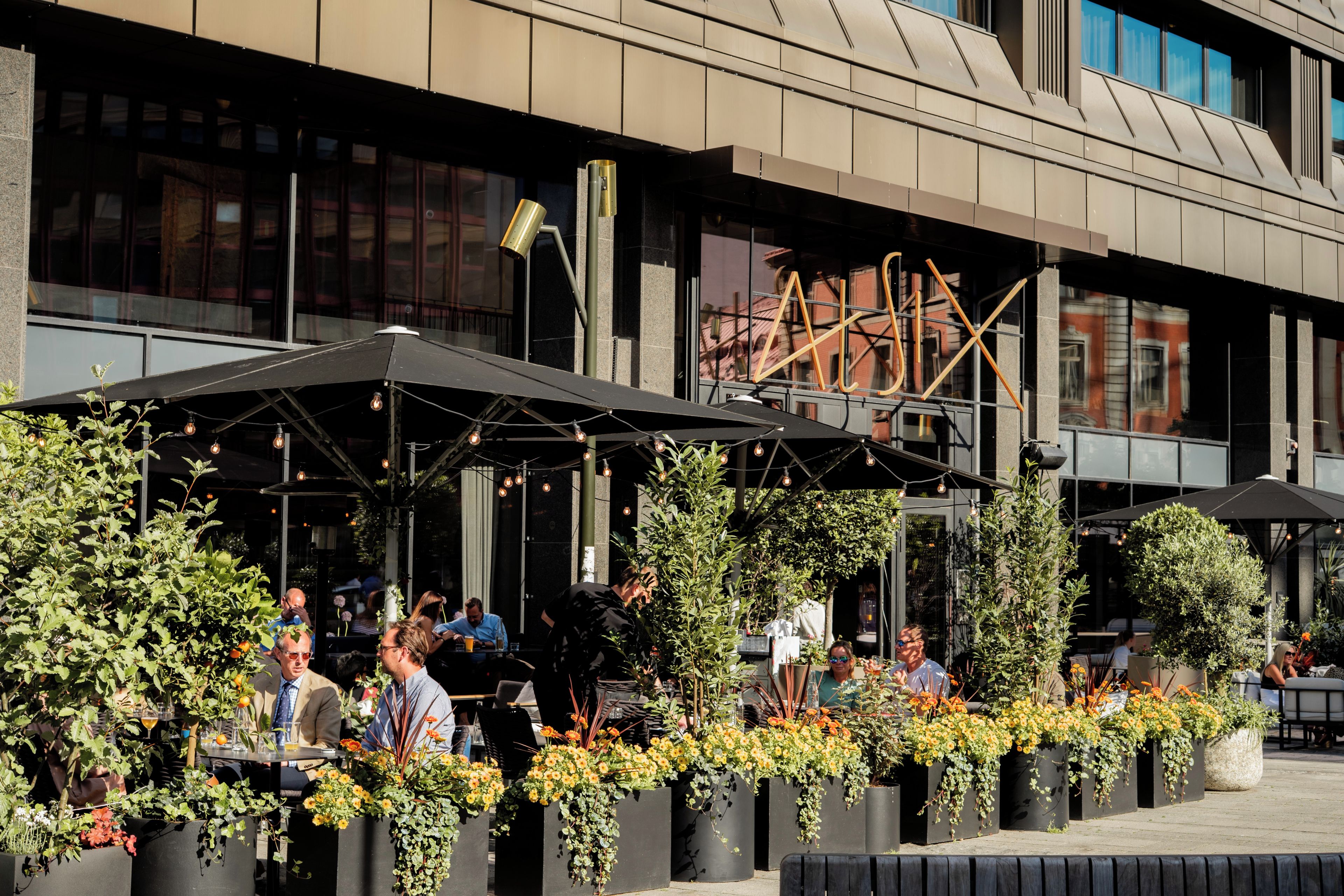 An outdoor seating area with tables, chairs, and potted plants.