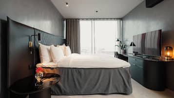 Et moderne hotelværelse med en stor seng, et skrivebord, et fjernsyn og udsigt over byen.