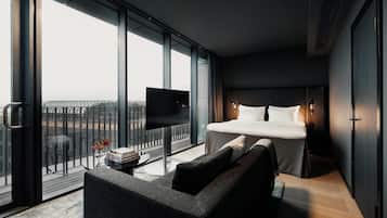 A modern hotel room with a large bed, a flat-screen TV, a sofa, and a balcony with a view.