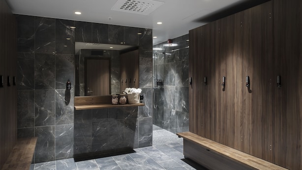 A modern bathroom with marble walls, wooden cabinets, and a bench.
