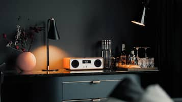 A modern interior with a dark wall, a desk with a radio, a lamp, and various bottles.