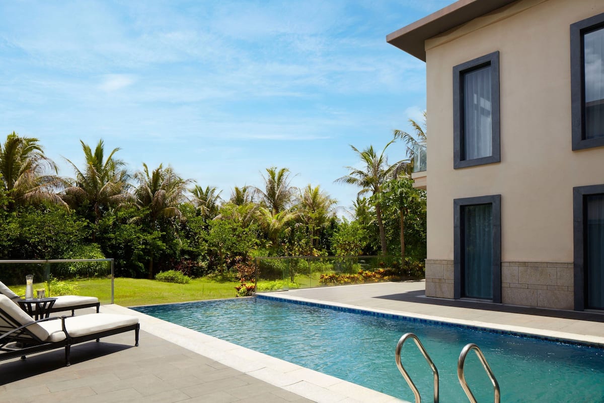 A modern pool area with lounge chairs, a clear pool, and a building with large windows.