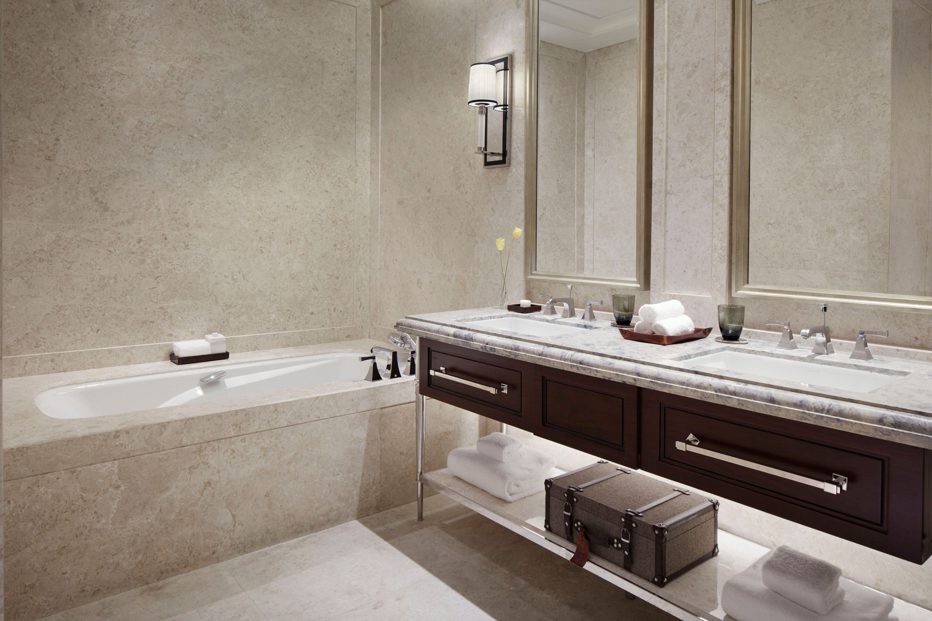 A modern bathroom with a double sink vanity, a large mirror, and a bathtub.