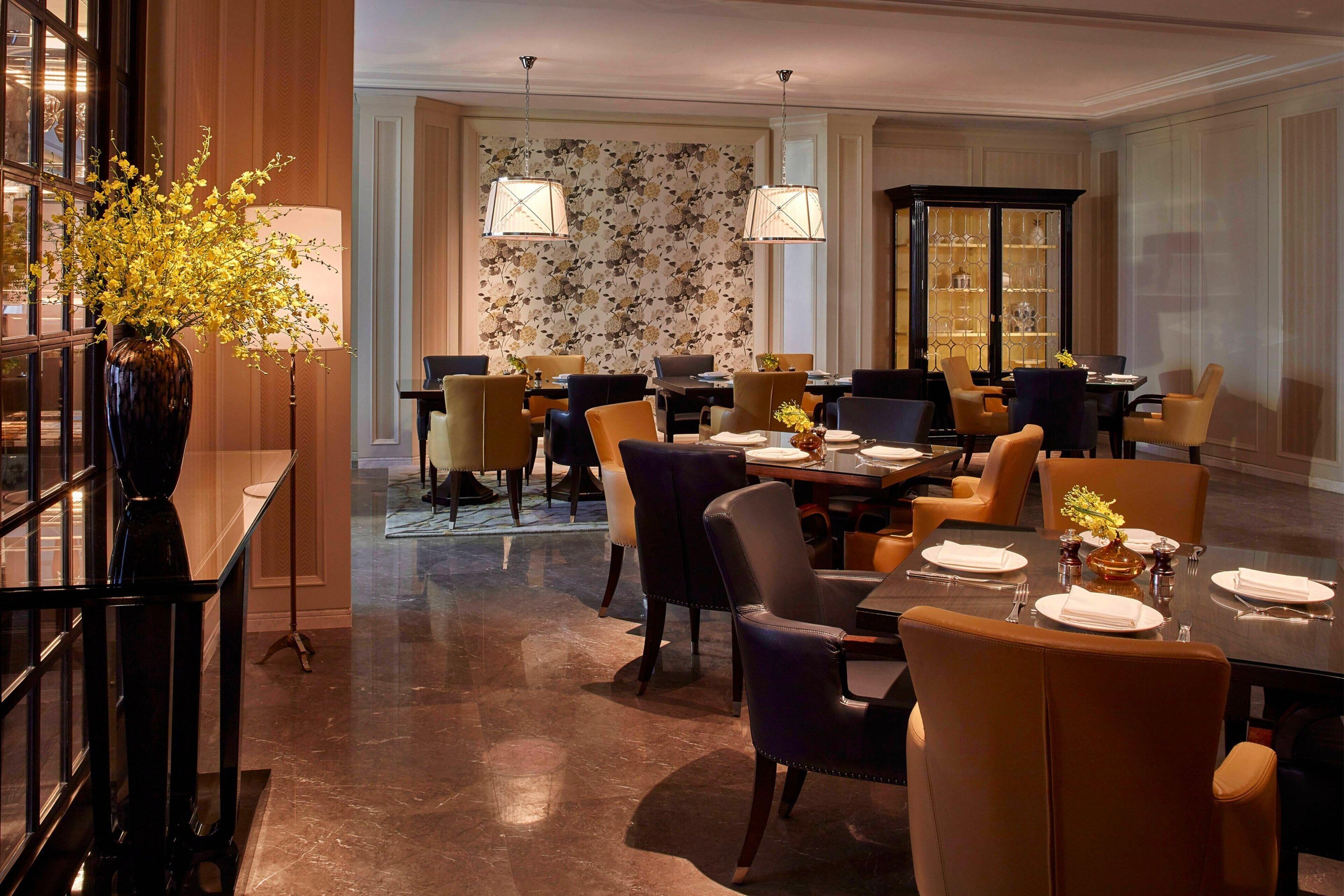 A dining area with a large table, multiple chairs, and a cabinet with glassware.