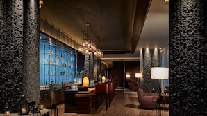 A bar area with a wooden bar counter, stools, and a blue illuminated shelf displaying bottles. - The Ritz-Carlton, Haikou (Haikou)
