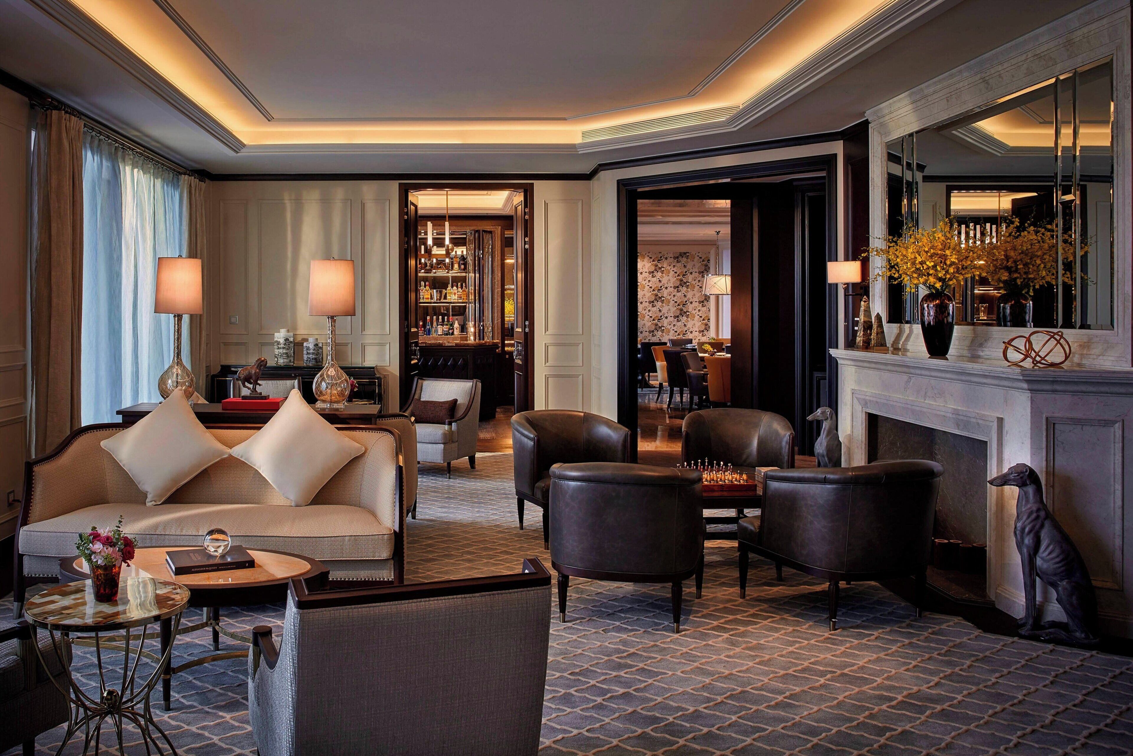 A well-appointed hotel lobby with a sofa, armchairs, a coffee table, and a fireplace.