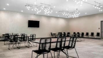 Un salón de conferencias con una gran mesa, varias sillas, un televisor de pantalla plana e iluminación de techo moderna.