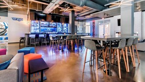 A modern hotel lobby with a bar area, seating arrangements, and a visible 'HOTEL' sign.