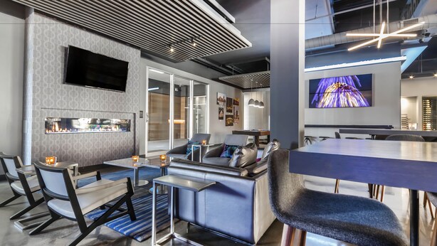 A modern interior with a bar area, seating, and a large TV screen.