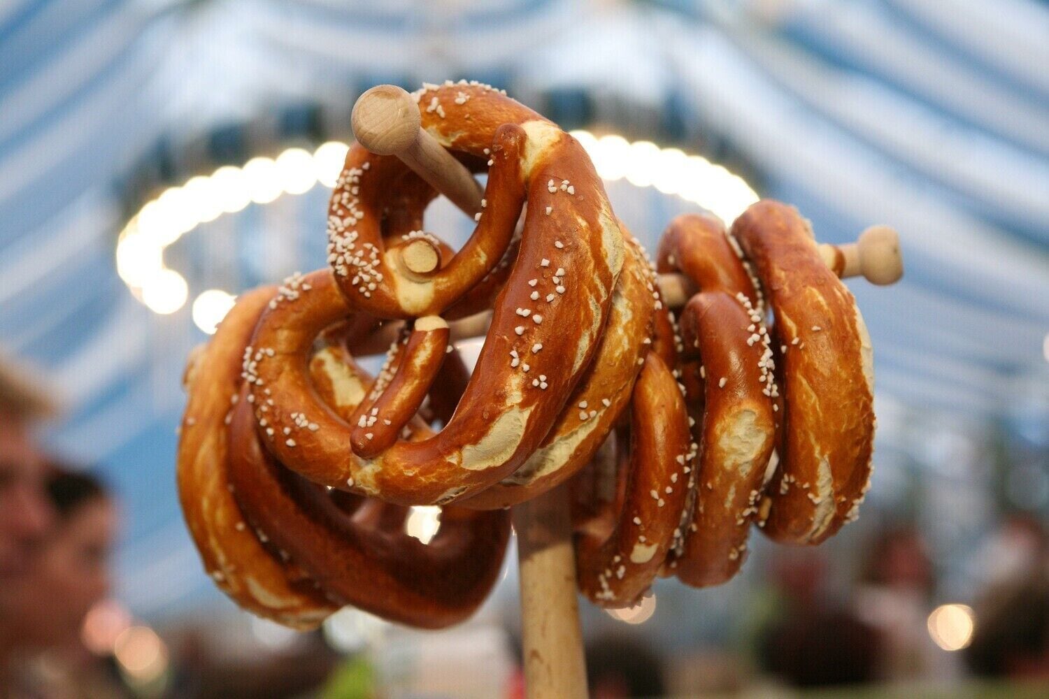 Un bâton de bois auquel sont fixées plusieurs bretzels, chacun saupoudré de graines de sésame blanches.