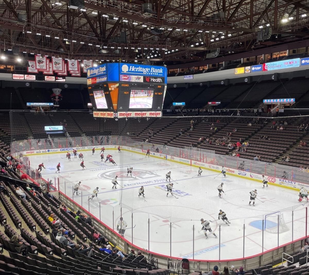 An indoor ice hockey rink with multiple teams playing, surrounded by spectator seating.