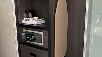 A modern hotel room with a built-in wardrobe, a coffee machine, a hairdryer, and a small shelf with toiletries.