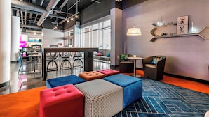 A modern lounge area with seating, a bar, and a large window providing natural light.