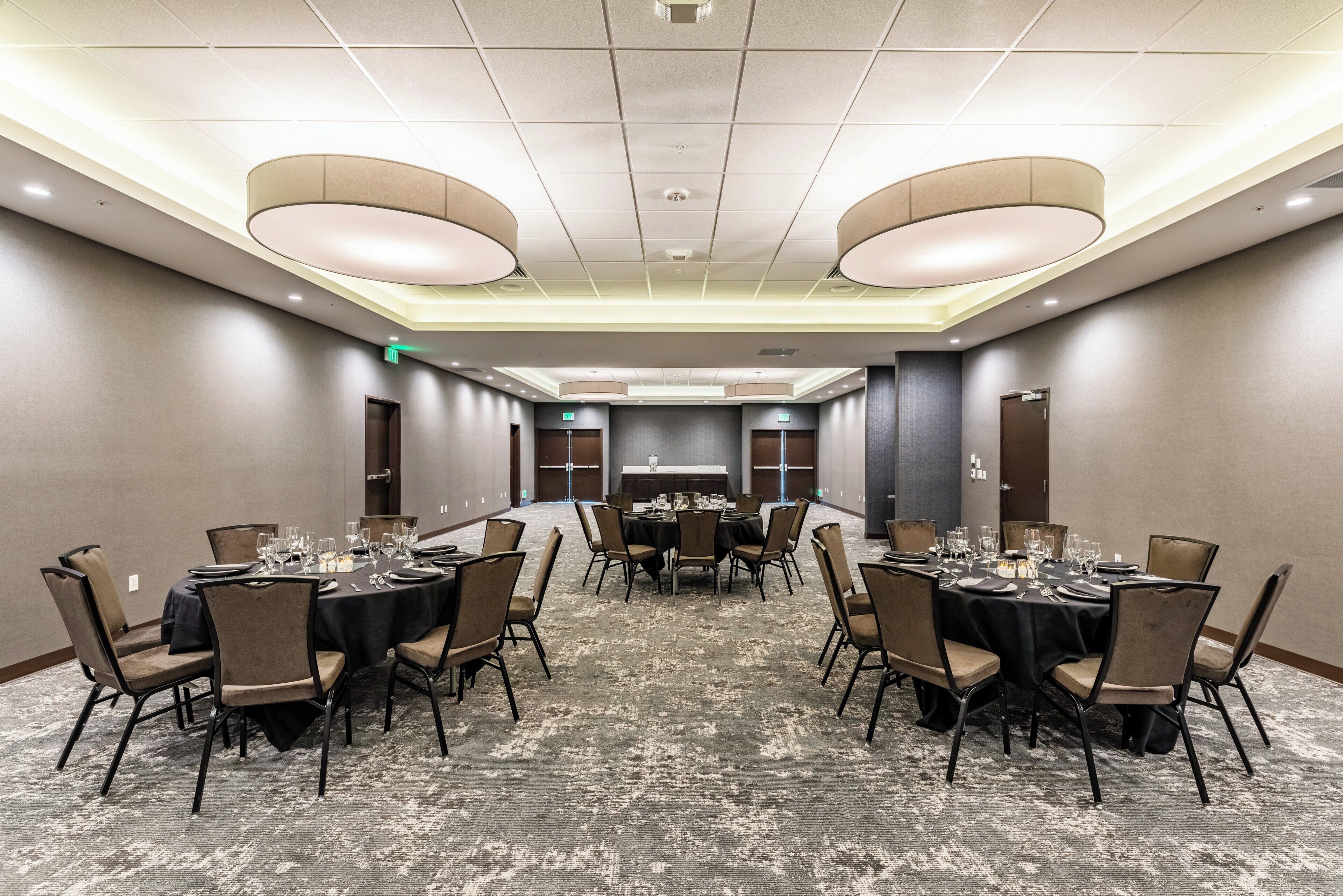 A conference room with round tables, chairs, and a carpeted floor.
